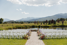 a lake wedding ceremony with white chairs and flowers.