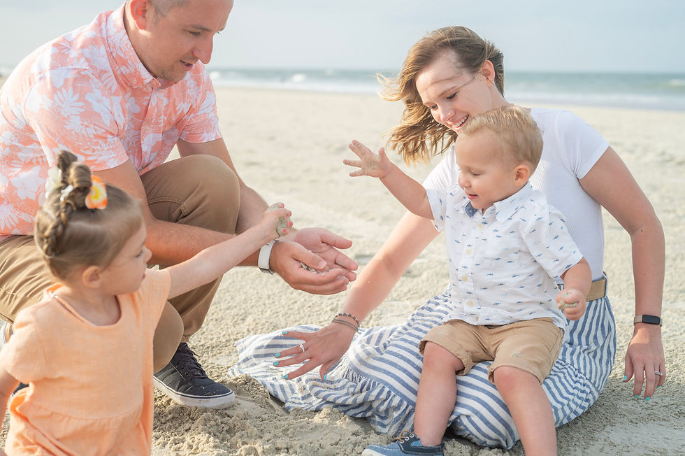 A family of four playing with sand on a beach.