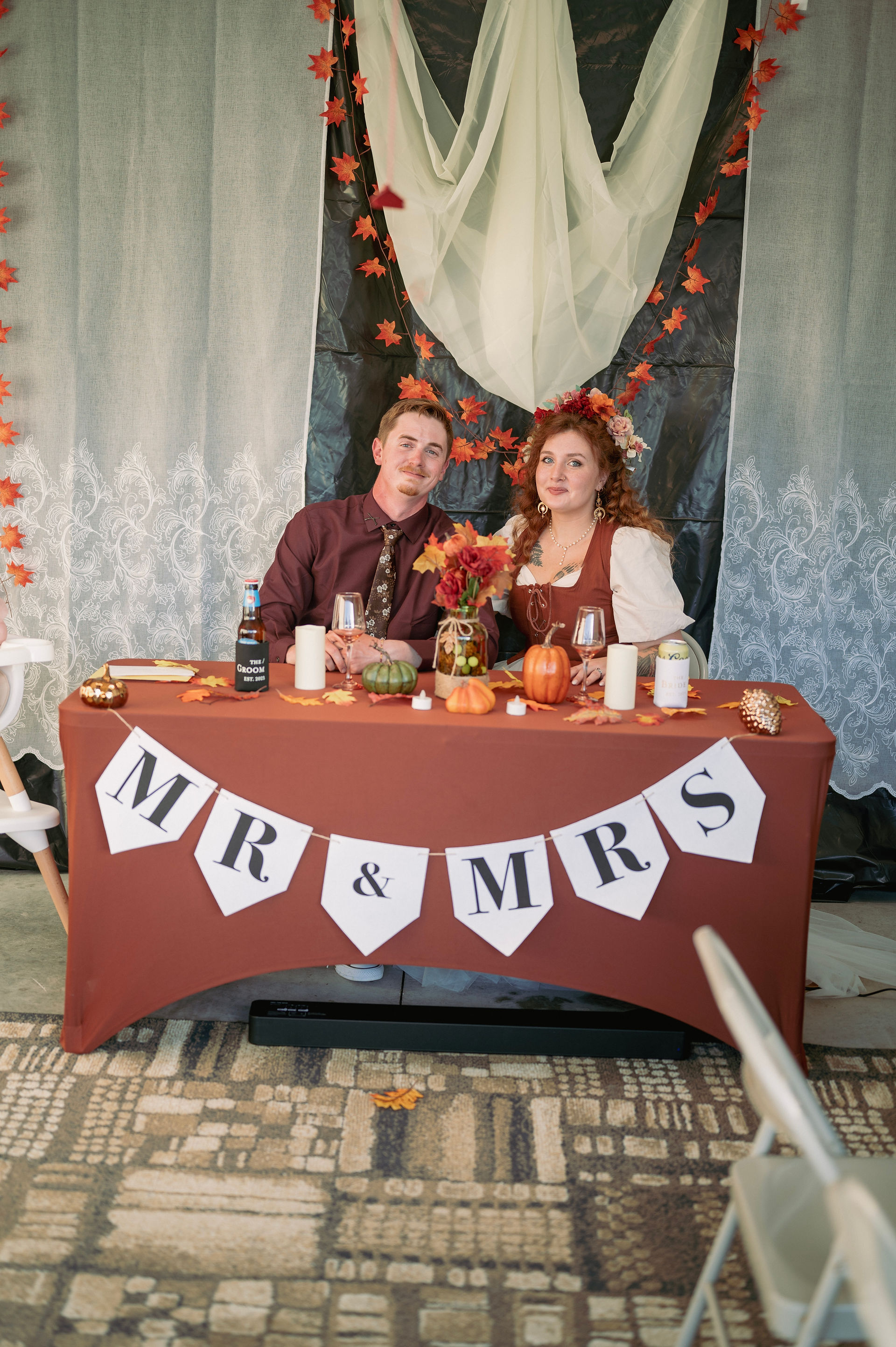Bride and groom sitting at the head table with a banner that says Mr and Mrs 