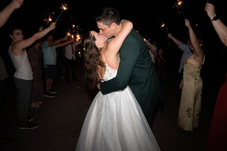 Bride and groom kissing in front of a sparkler tunnel.