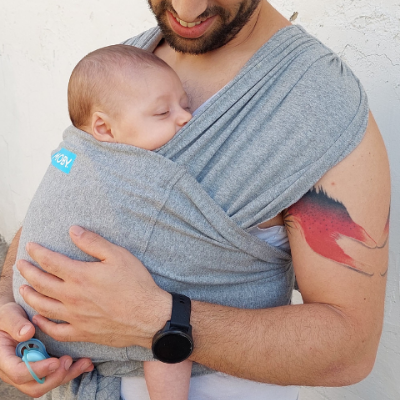 אבא עם תינוקת במנשא בד ביום קיץ חם, שניהם בלבוש מינימלי