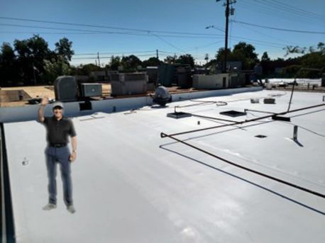 Man waves on a flat white rooftop near HVAC units, with another worker crouched in the background under a clear blue sky.