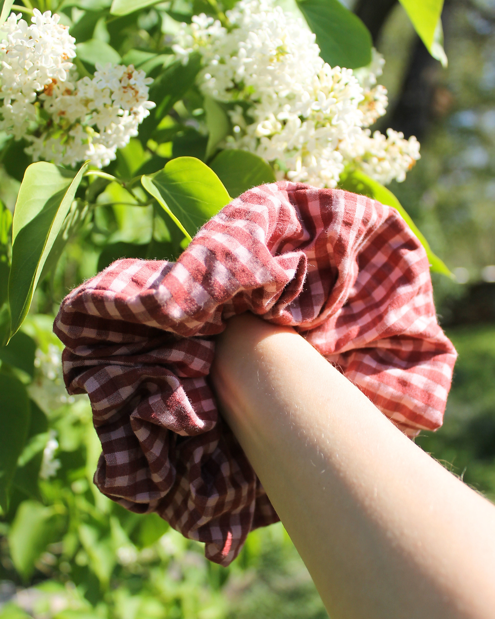 Chouchou cheveux à carreaux rouges et blancs porté au poignet, accessoire capillaire tendance en extérieur avec fleurs.
