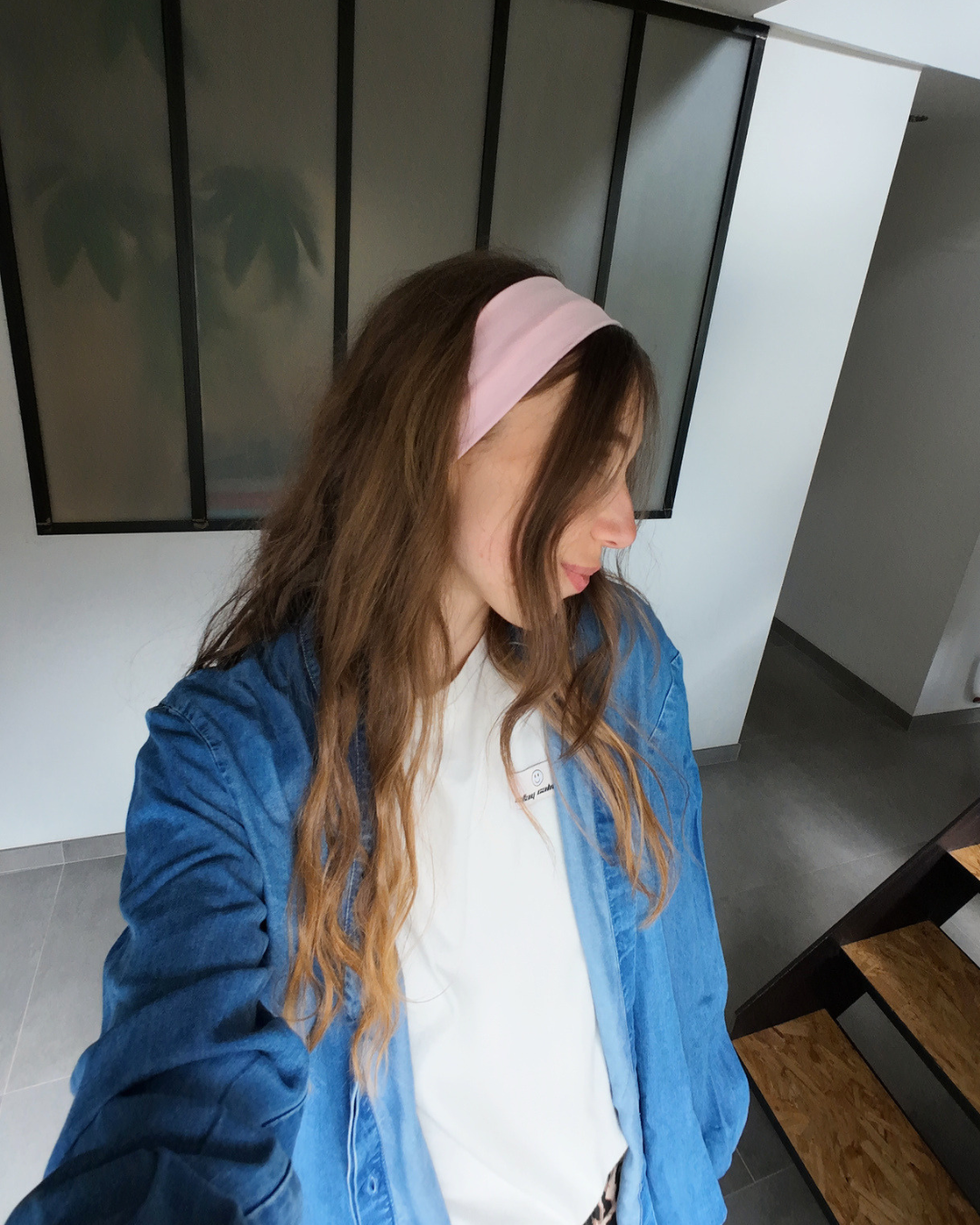 Femme de profil portant un bandeau rose dans les cheveux et une chemise en jeans