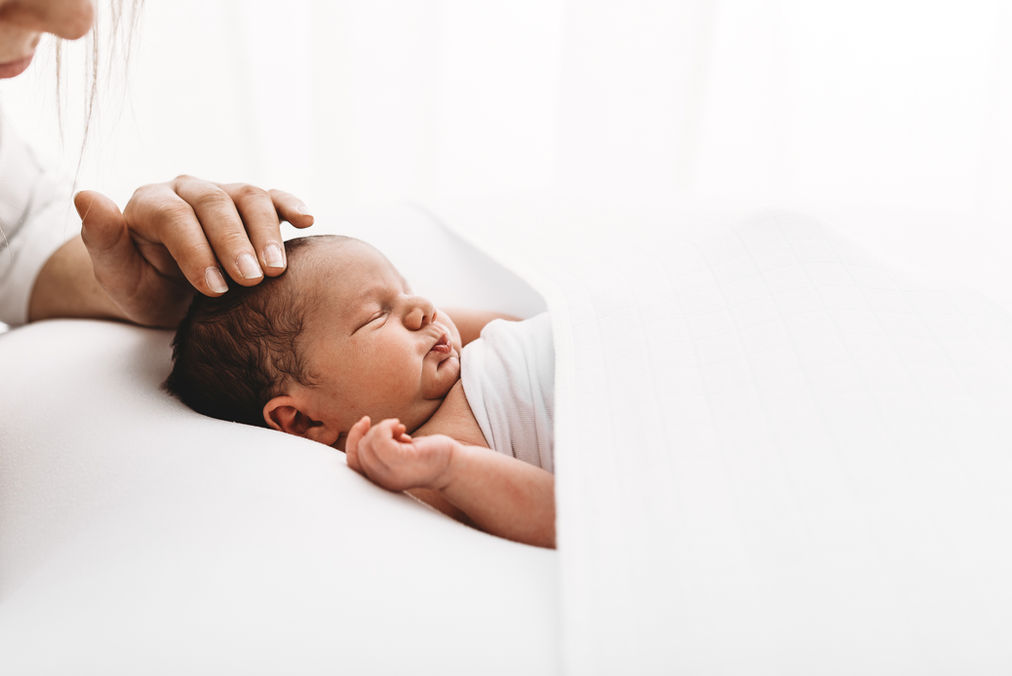 Newborn Baby being stroked on head during newborn photoshoot with Esher Photographer Rachel Fairfield Photography