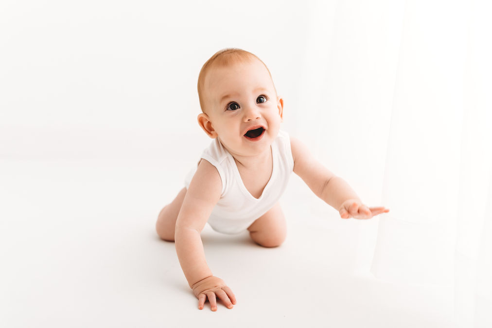 Baby boy crawling towards the camera, wearing a white vest, during baby photoshoot with Rachel Fairfield Photography, Esher Photographer