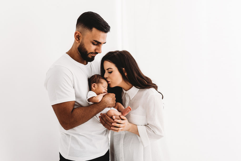 Mum and dad holding newborn baby girl in studio photoshoot with Esher Photographer Rachel Fairfield Photography