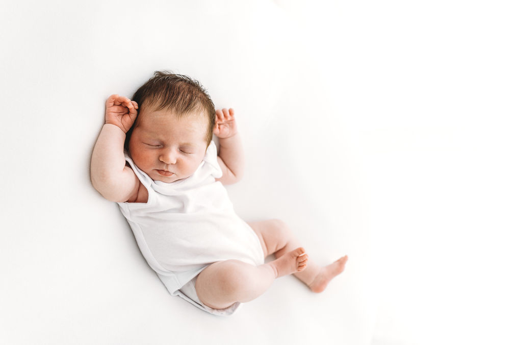 Sleeping newborn baby girl in white vest, taken during baby photo session with Esher Surrey photographer Rachel Fairfield Photography
