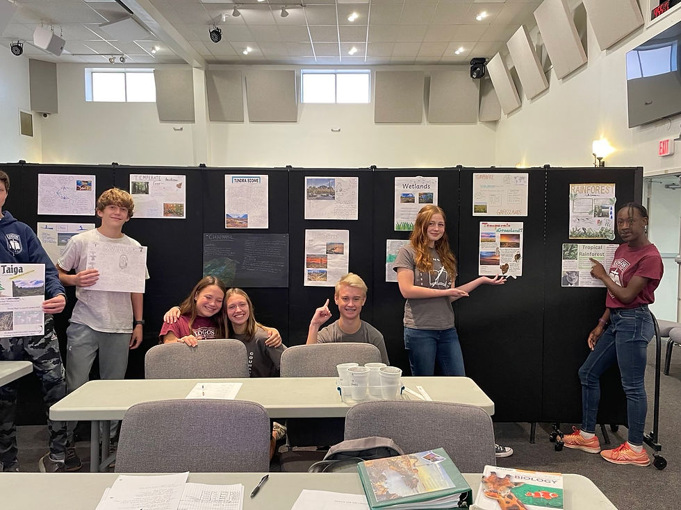 Students stand in front of posters of different biomes