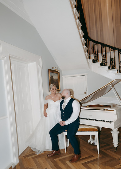 Editorial-style, flash photo of bride and groom sitting at a piano