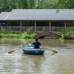 Man rowing a boat to Horne's Place Oast pool house