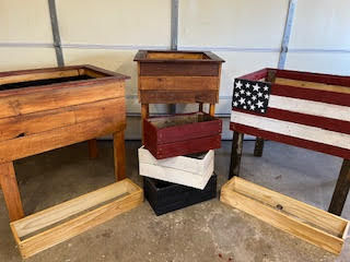 A variation of garden boxes, some have legs and some have none. Each are painted or stained different colors. They all vary in size, height, and width.