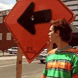 Person playfully turning a street direction arrow