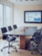 Conference room with graphs on screen, ready for a business meeting.