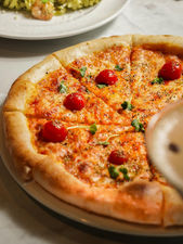 Cheese and pepperoni pizza with fresh basil in hotel restaurant.