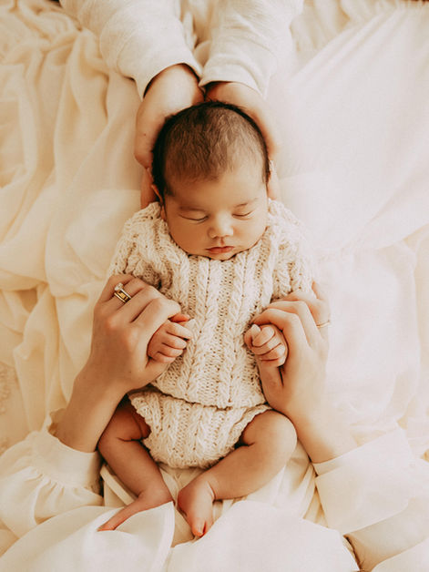 calgary newborn photography newborn on moms lap with dads hands holding him