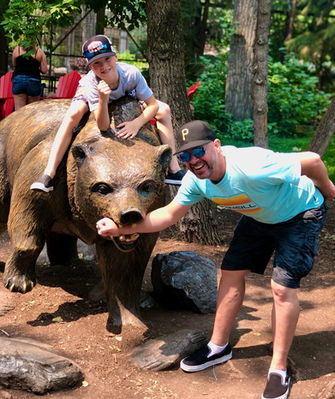 boy sitting on bear with dad's arm in it's mouth