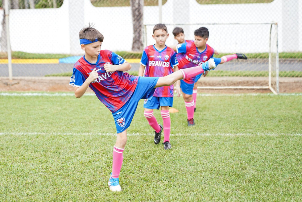Niño pateando balón en el campo con otros niños usando camisetas. Categorías Masculinas