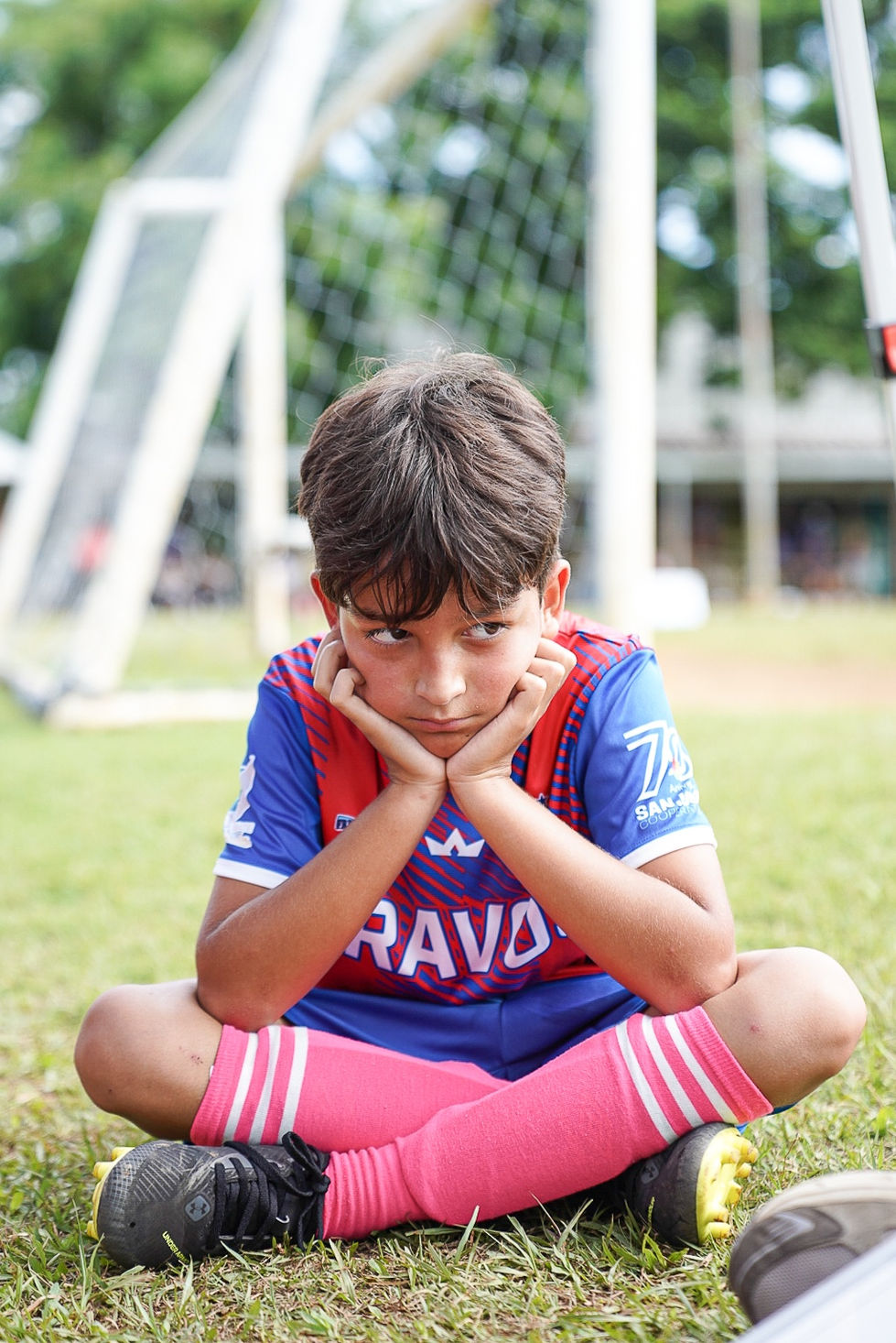 Niño pensativo mirando con brazos cruzados, camiseta Bravos, Categorías Masculinas Escuela De Futbol Bravos De Cidra