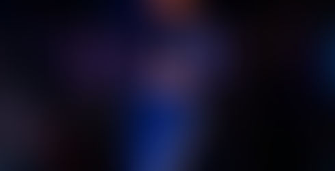 “Female singer performing on stage in a blue tracksuit, singing into a microphone and holding a feather duster.”
