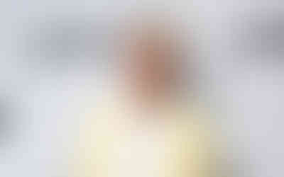 Actor in a pale yellow blazer and white T-shirt posing in front of a Tribeca Festival step-and-repeat backdrop.”