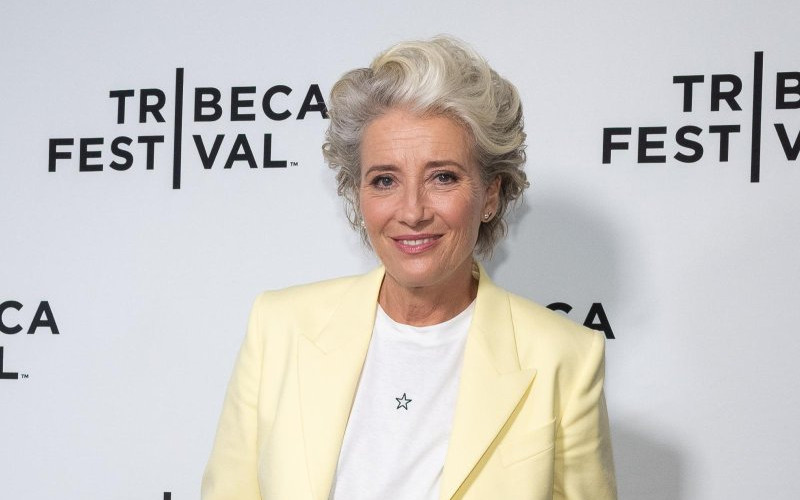 Actor in a pale yellow blazer and white T-shirt posing in front of a Tribeca Festival step-and-repeat backdrop.”