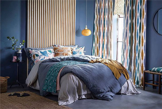 Stylish bedroom interior design, blue walls, patterned curtains