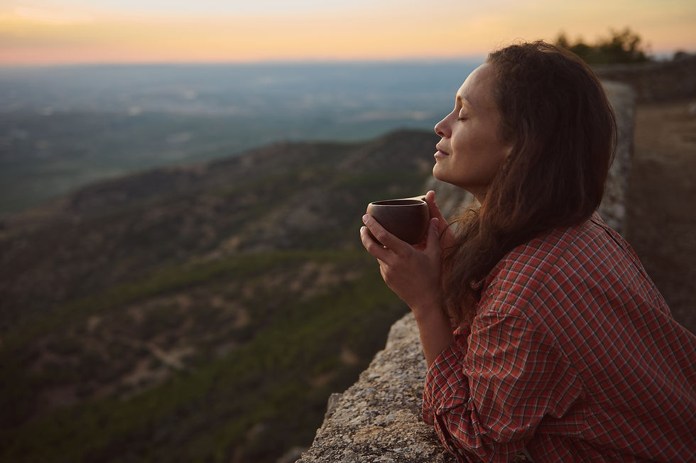 Woman with a cup of tea looking over a vista