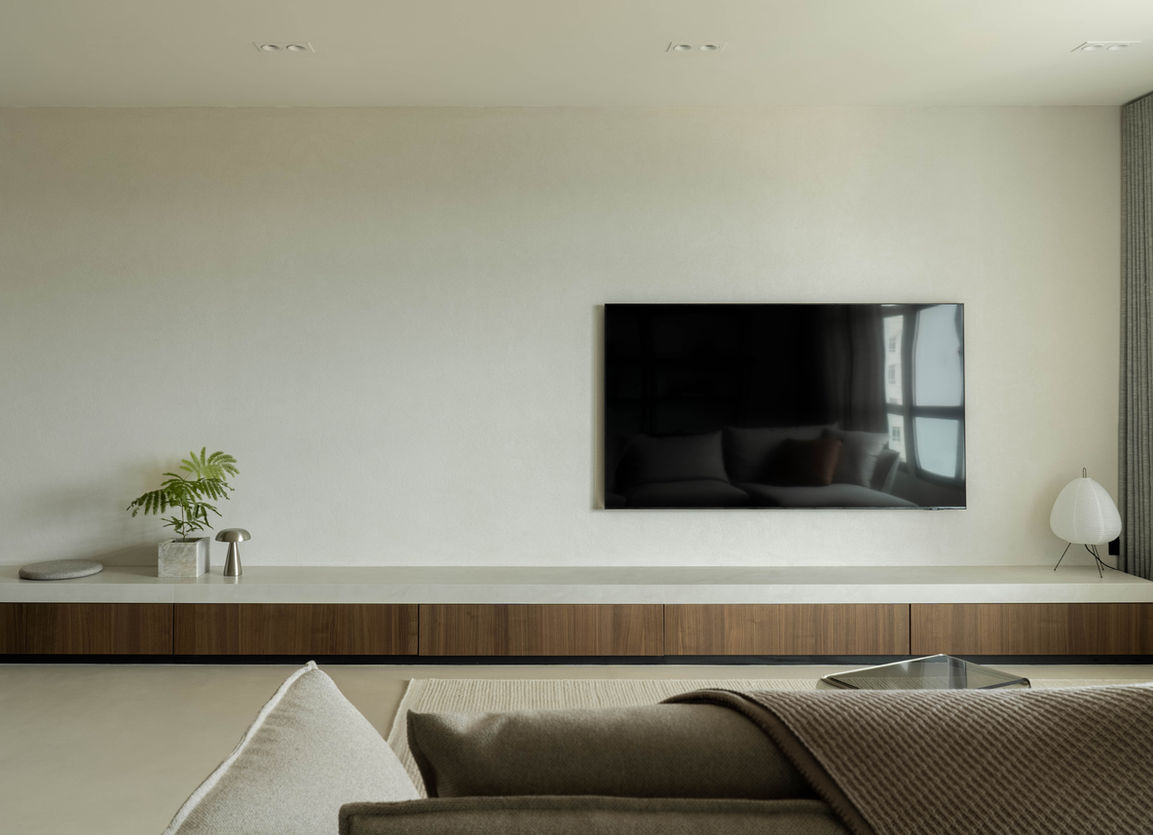 Minimal long stone bench doubling as a tv console against a mamarino textured feature tv wall. Contrast with nude tone microcement floors