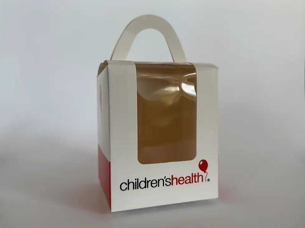 A cardboard small box with a plastic window opening and a handle of the top. Childrens Health logo is imprinted at the bottom front just underneath the plastic window
