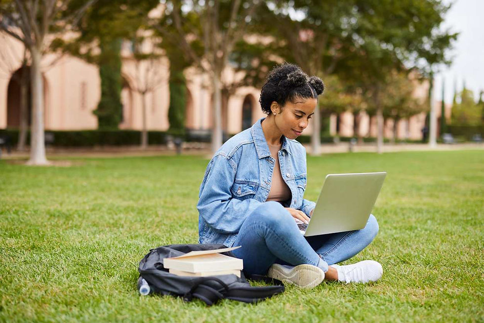 Female college student doing homework on a laptop on campus lawn