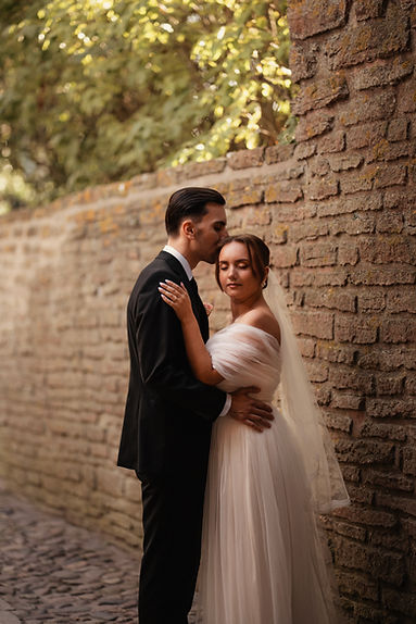 Bröllopsporträtt när brudgummen kysser bruden på huvudet