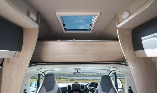 Interior view of a motorhome with a skylight and raised bed over the cab.