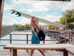 Surfer walking down the pier
