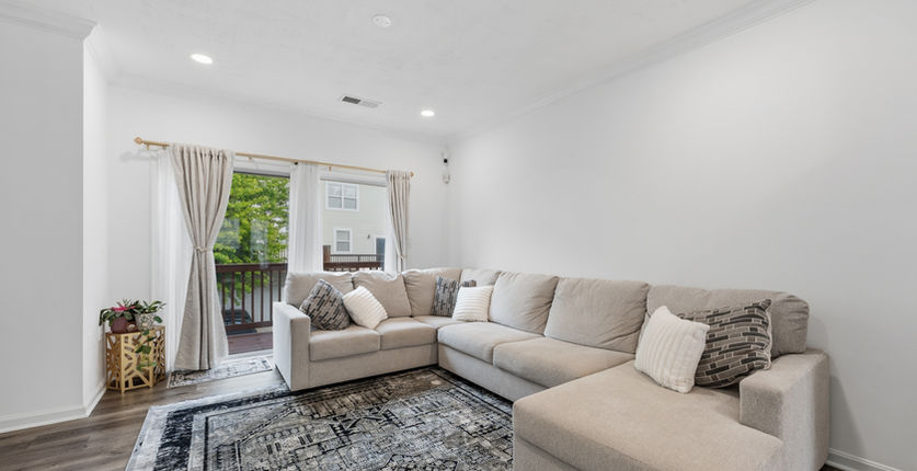 Living room with large sectional sofa and sliding glass door to the deck