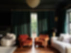 Sunlit living room with green curtains, orange chairs