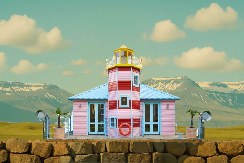 Pink lighthouse with red stripes stands on a stone wall, mountains in background.