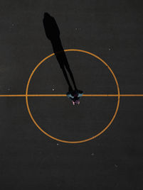 Drone aerial view of a basketball playground, dropping small water balloons onto a dartboard-like target, scoring points in a fun game.