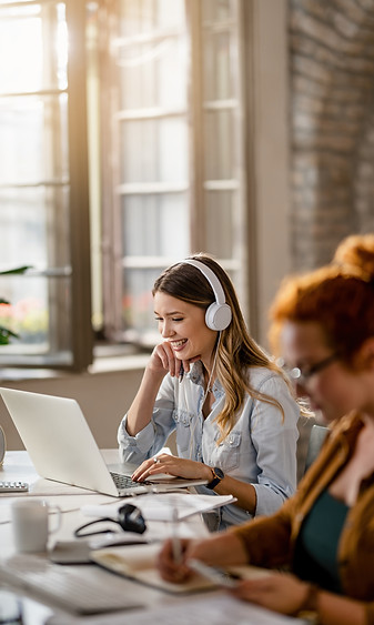 happy-female-freelancer-working-computer-while-listening-music-headphones-office.jpg