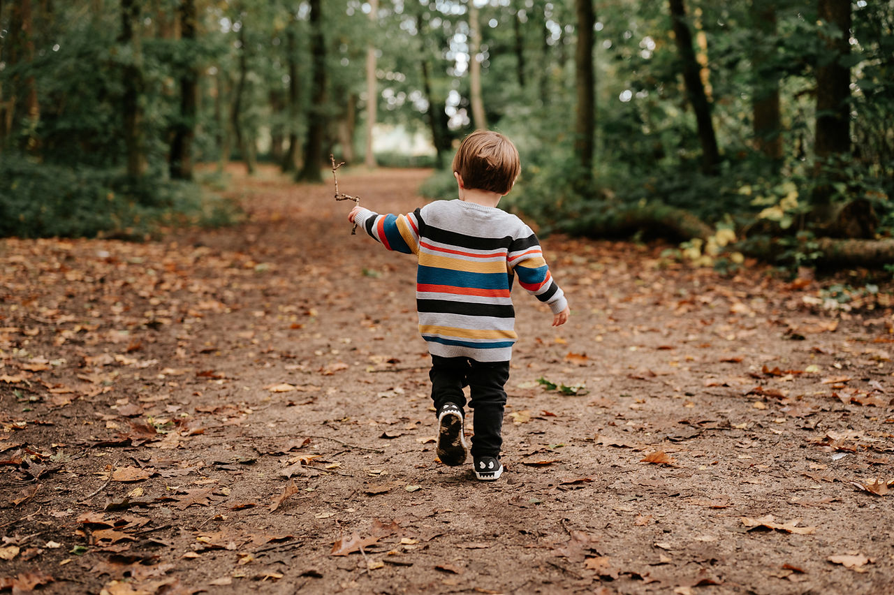 boy walking away in woods