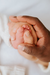 Close-up newborn baby feet being gently held by parents in natural light studio photography session