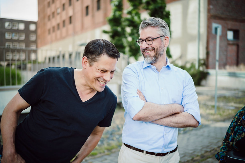 Zwei lachende Männer vor urbaner Kulisse