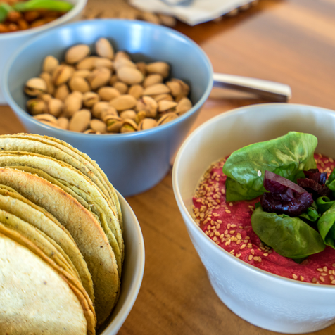 Tortillas, nueces y salsa de frutos rojos en platos pequeños sobre una mesa de madera clara.