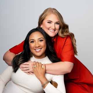 Smiling women embracing, red and cream outfits