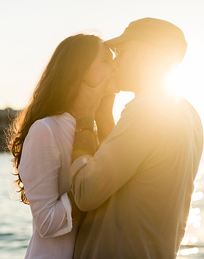 Man and woman in sunset by ocean kissing for protector hero romance books