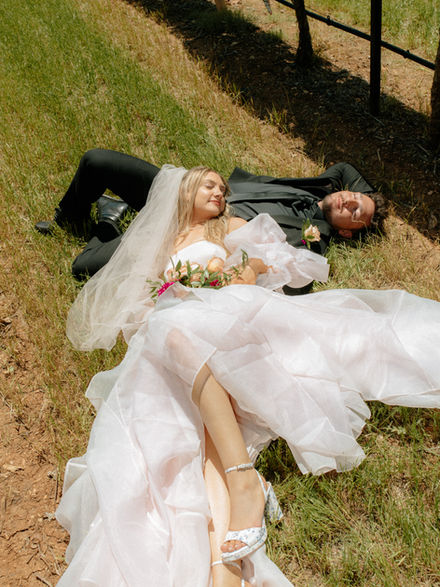 bride and groom laying in the vineyard in Fredericksburg