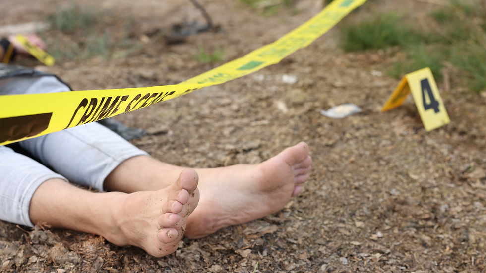 Bare feet and legs of a person lying on the ground under yellow crime scene tape, marker "4" nearby on dirt surface.