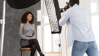 A woman sits and smiles as she has her portrait taken in-studio by a professional photographer.