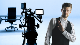 A businessman has his hand up against going on camera to speak. A recording studio setup is waiting for him.