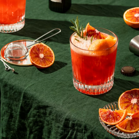 A handcrafted cocktail garnished with blood orange and rosemary, celebrating Guatemala City's vibrant cocktail scene.